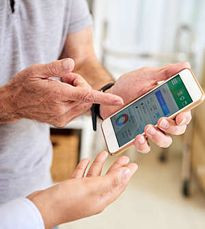Senior gentleman pointing to the data on his smartphone health app as he discusses with his doctor.